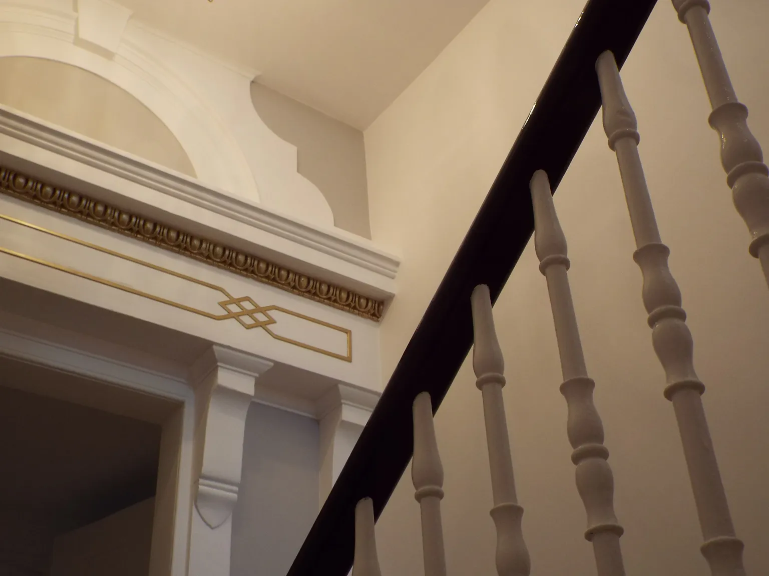 archway in hall that has a white and gray background with gold highlighting